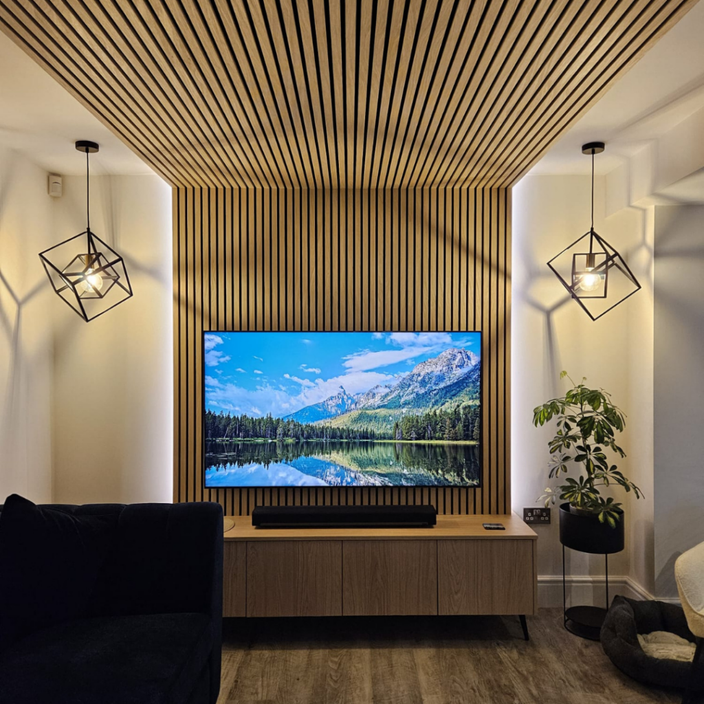 Custom oak media wall installation in Broadstone featuring integrated TV, acoustic panelling, floating storage and feature lighting.