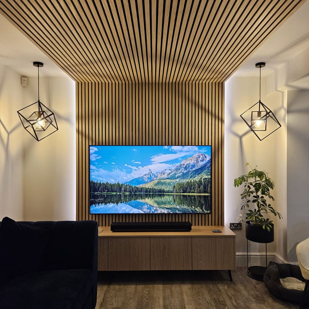 Contemporary oak media wall featuring slatted timber panelling, integrated shelving and a wall-mounted television.