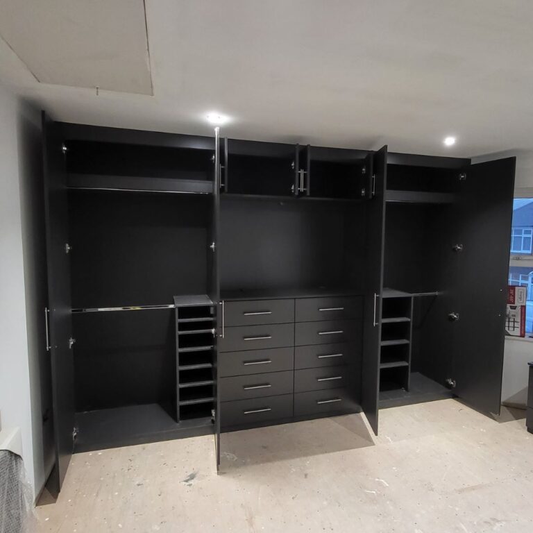 Bespoke fitted wardrobe with integrated shelving, drawers and hanging rails for organised bedroom storage.