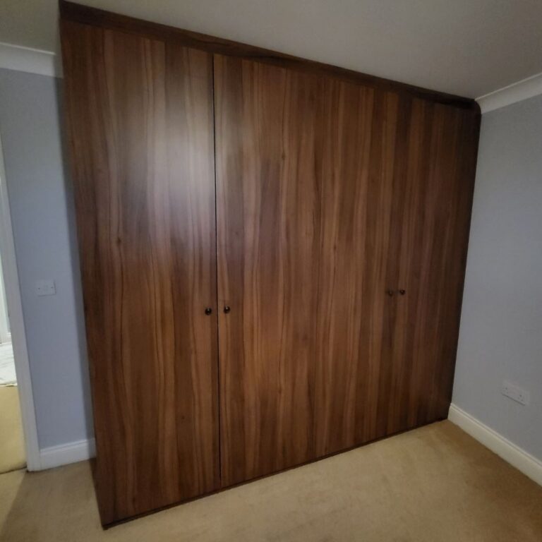 Dark wood-effect fitted wardrobe with full-height doors providing bespoke bedroom storage.