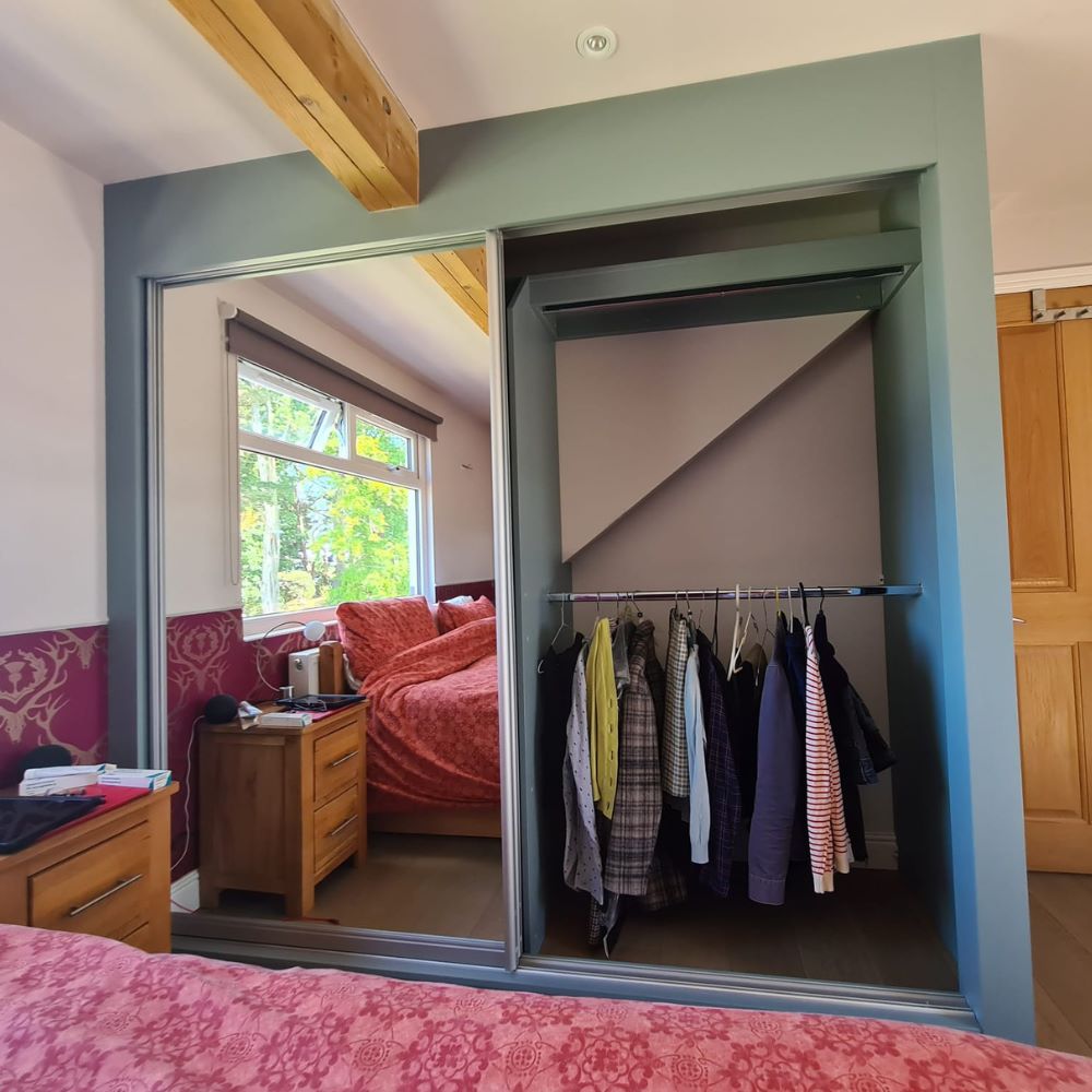 Fitted sliding wardrobe with mirrored doors, integrated hanging rail and bespoke bedroom storage designed to maximise space.